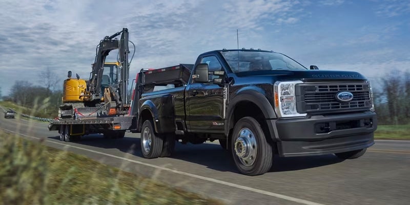 front view of a black 2024 Ford Super Duty F-250 towing a trailer down a road