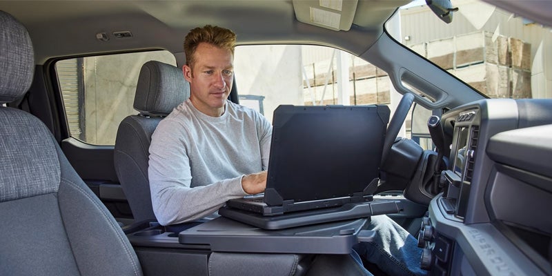 man on a computer lap top sitting in a 2024 Ford Super Duty F-250